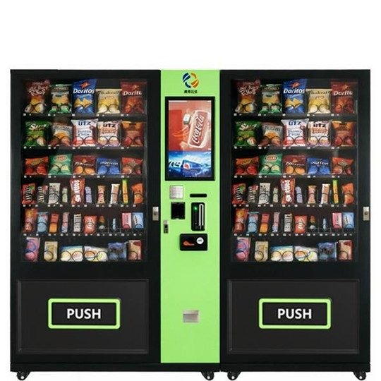 Two modern black and lime green vending machines side-by-side, fully stocked with various snacks and bottled drinks for high-traffic locations.